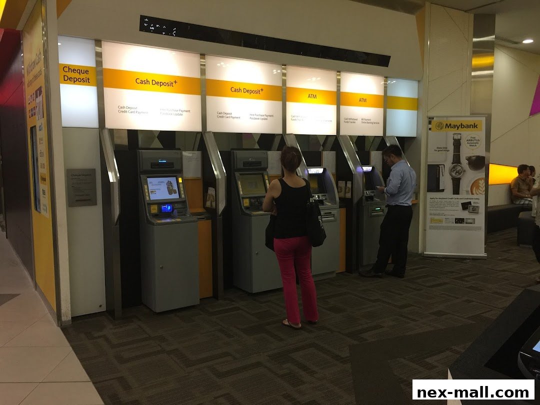 People using Maybank ATMs and cash deposit machines in a modern banking area.