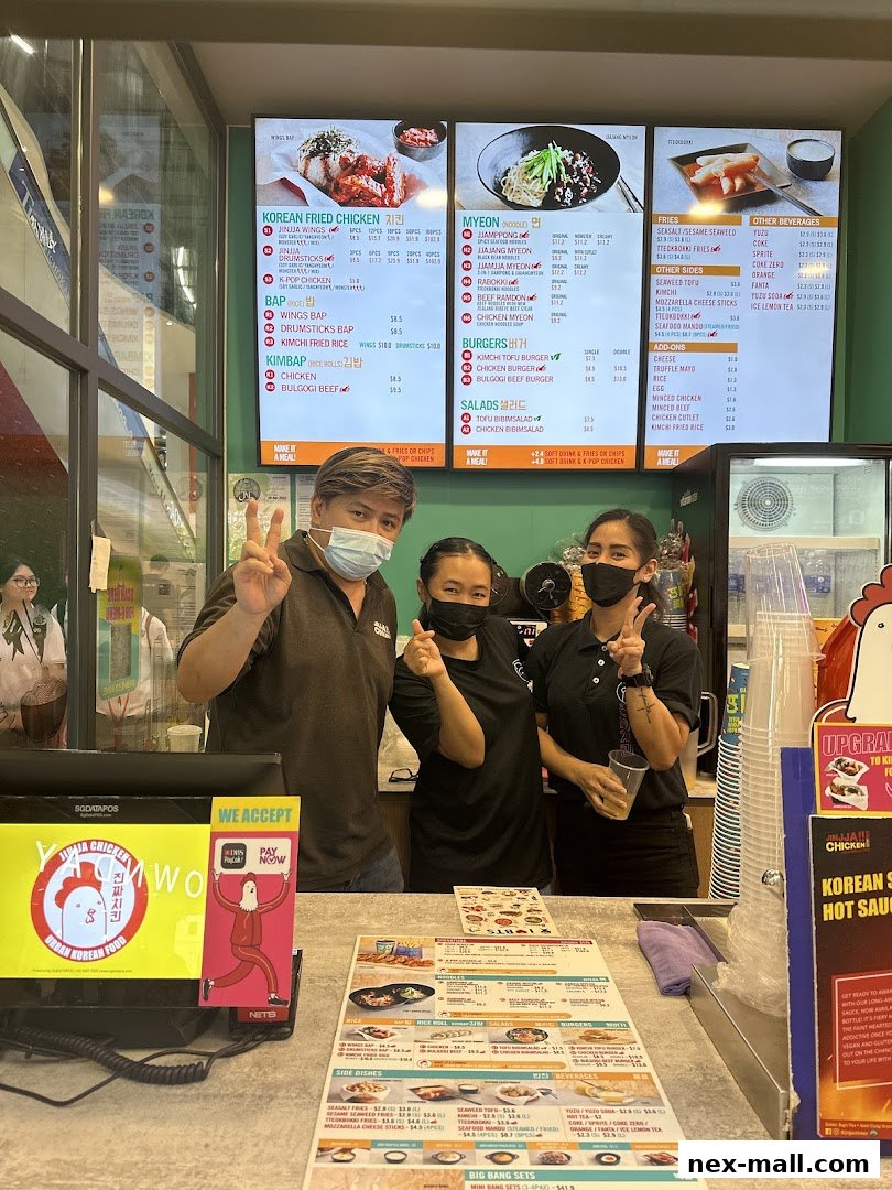 Three staff members pose behind a counter with a digital menu board and printed menus.