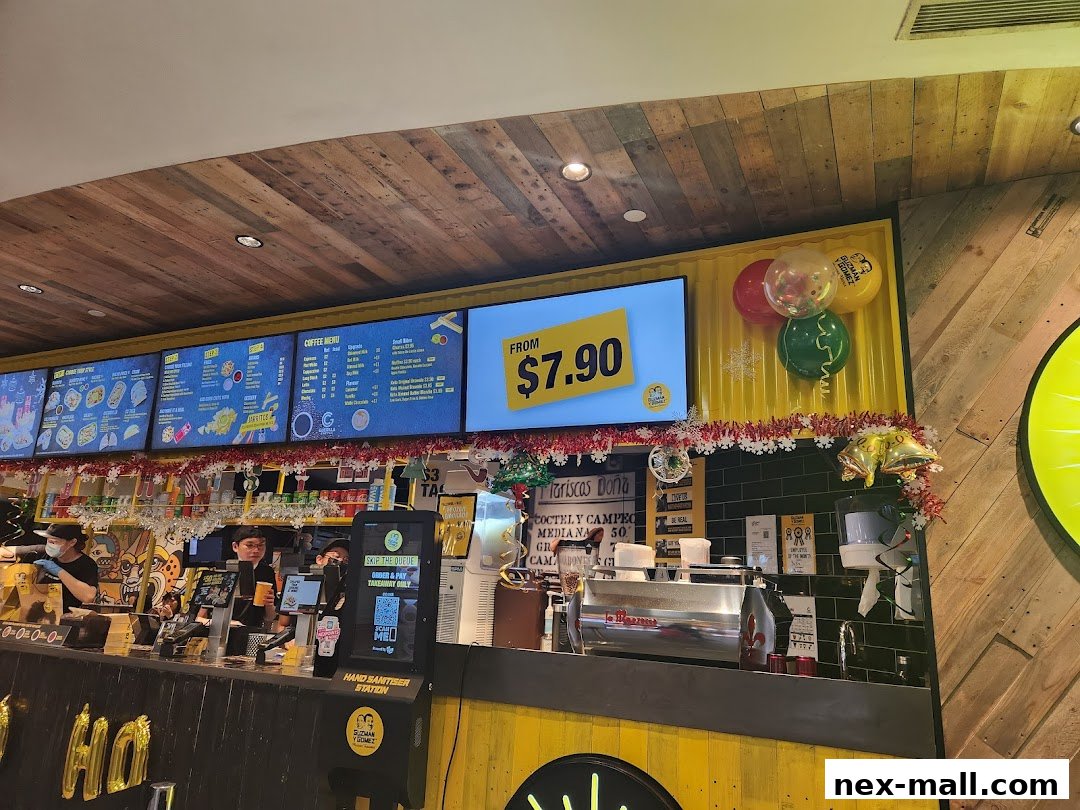 A lively counter at Guzman y Gomez with digital menus, staff, and festive decorations.