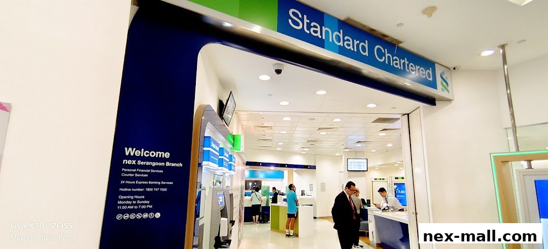 Entrance to a Standard Chartered Bank branch with ATMs and staff serving customers.