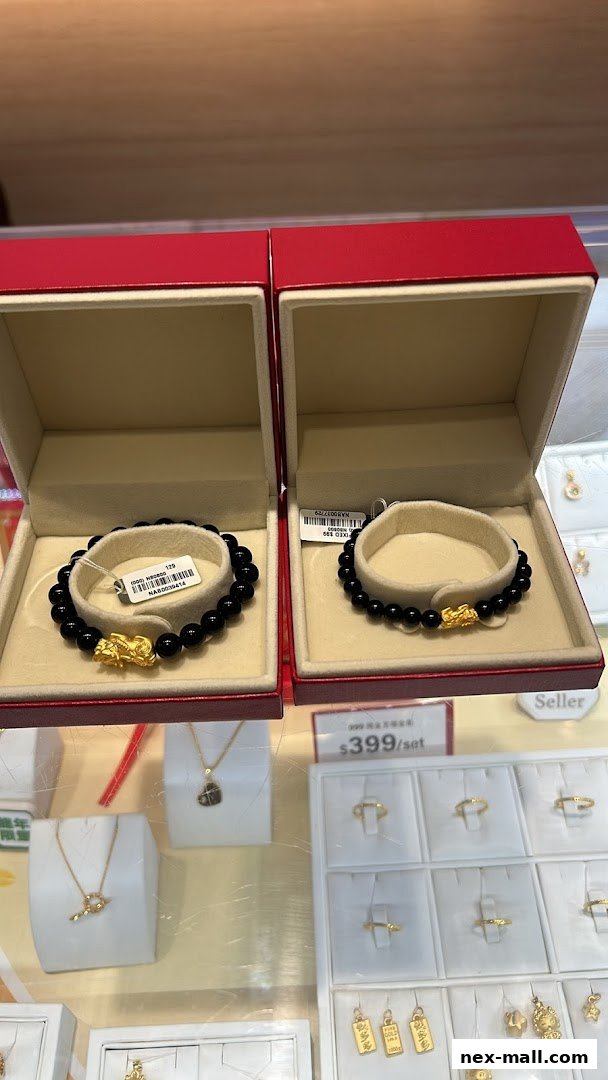 Two black beaded bracelets with gold charms displayed in red gift boxes, alongside other jewelry.