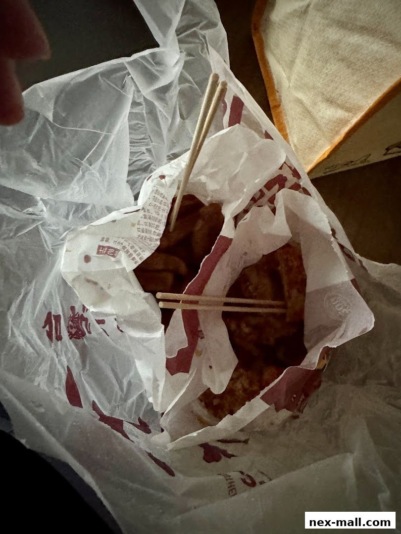 A paper bag filled with fried snacks and chopsticks from Shihlin Taiwan Street Snacks.