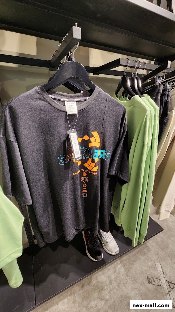 A display of Skechers t-shirts and apparel, featuring a dark t-shirt with a colorful logo and other garments on hangers.