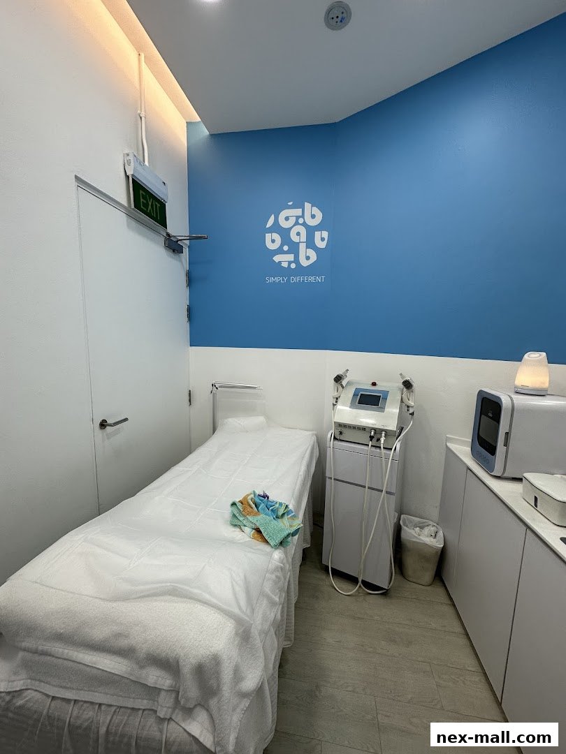 A clean treatment room with a bed, medical equipment, and a logo on the wall.