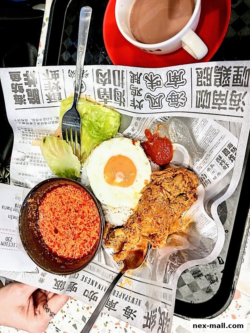 A plate of Hainanese fried chicken drumstick with rice, fried egg, and chili sauce, served with a drink.