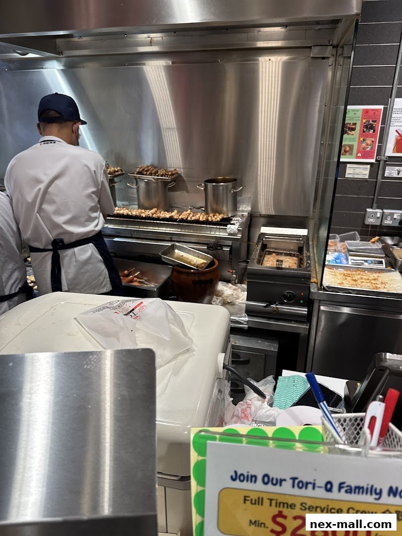 A chef prepares skewers of food on a grill in a commercial kitchen.