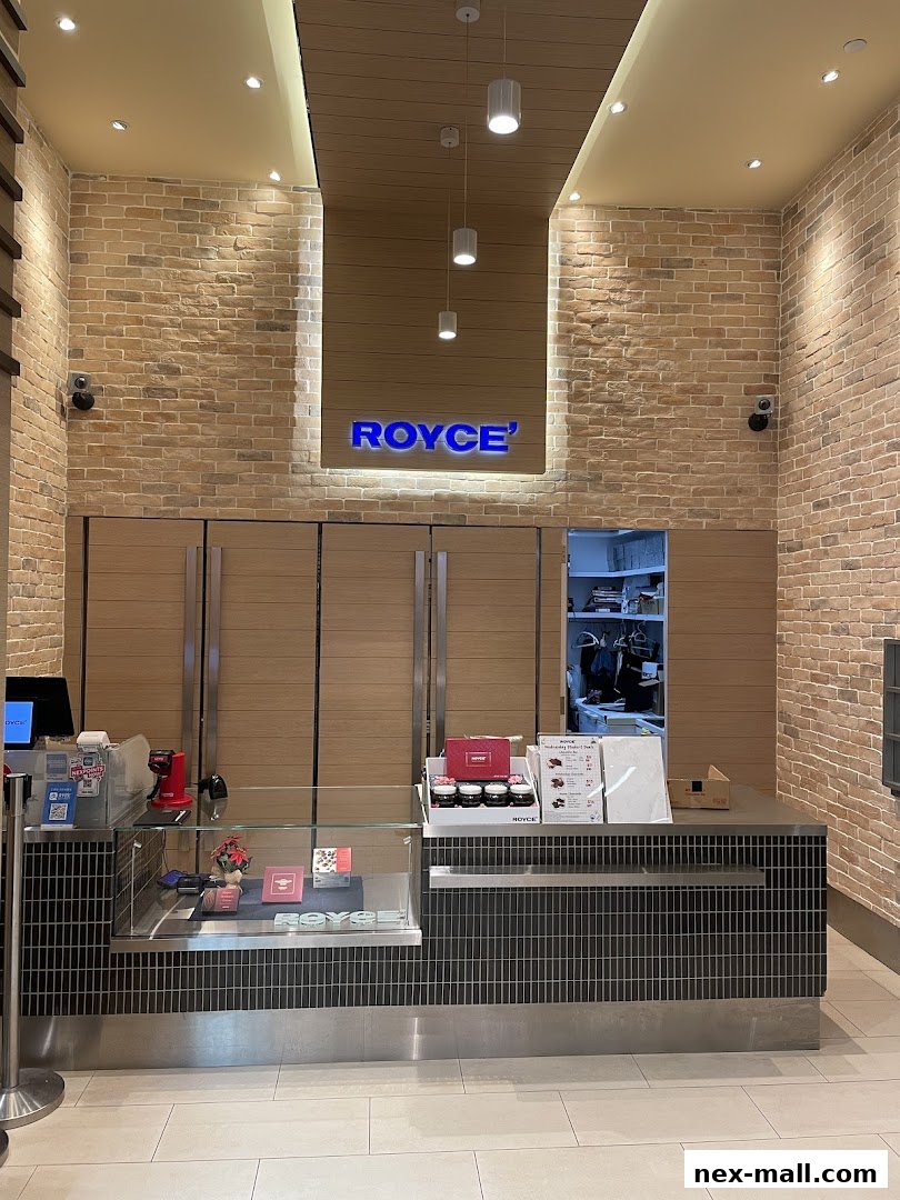 The Royce shop front features a modern counter with display cases and the illuminated Royce logo above.