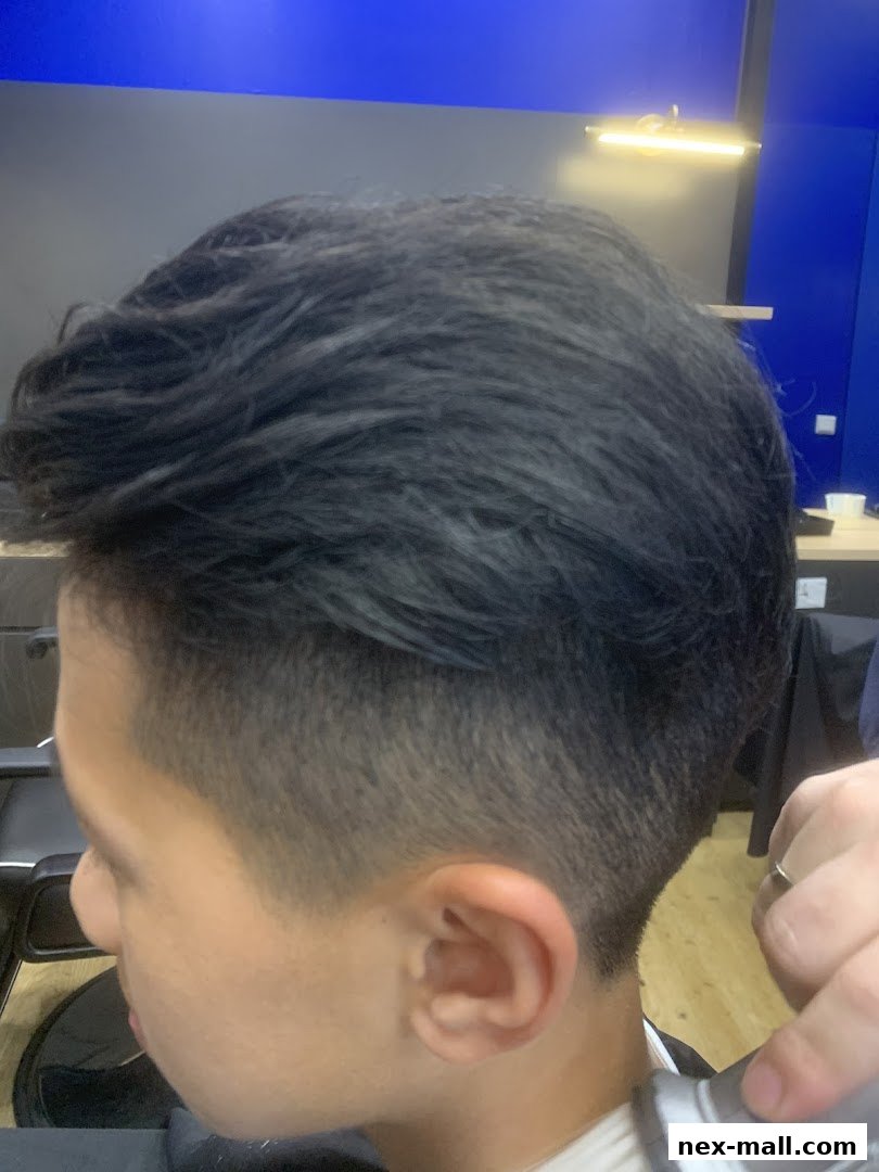 A barber is trimming the hair of a young person with a clipper.