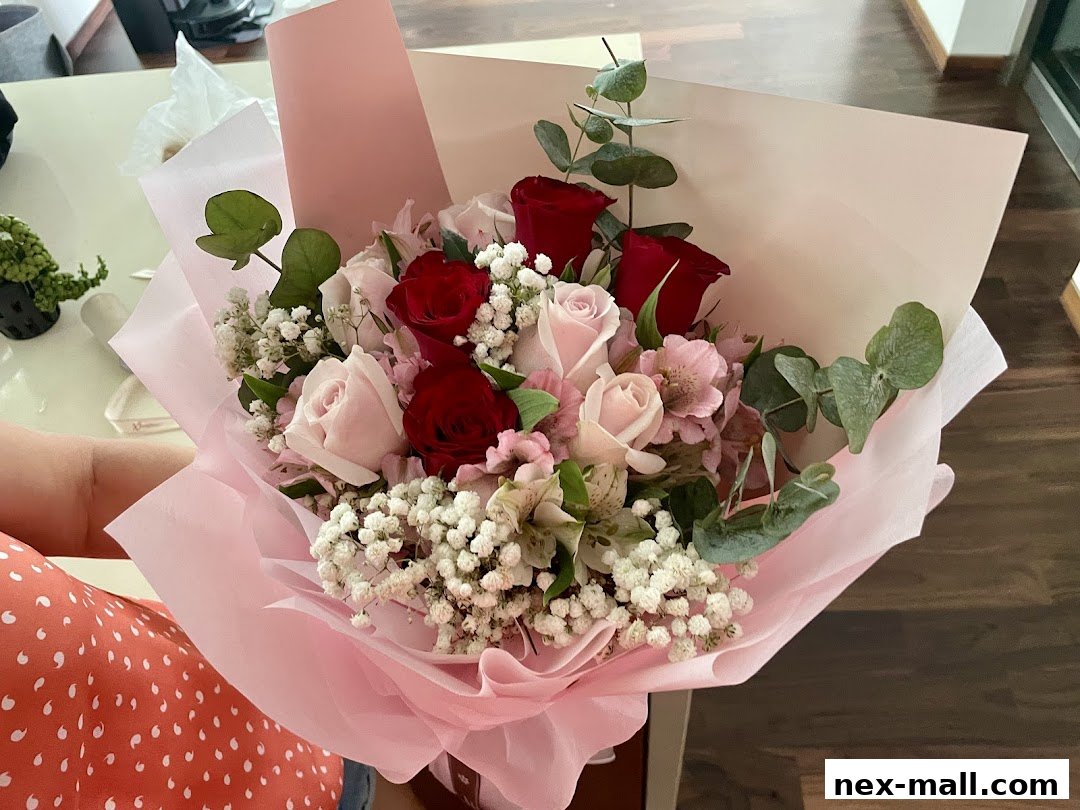 A person holds a beautiful bouquet of red and pink roses with baby's breath and eucalyptus.