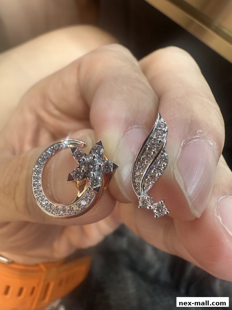 Close-up of a hand holding two sparkling diamond earrings, one shaped like a shooting star.