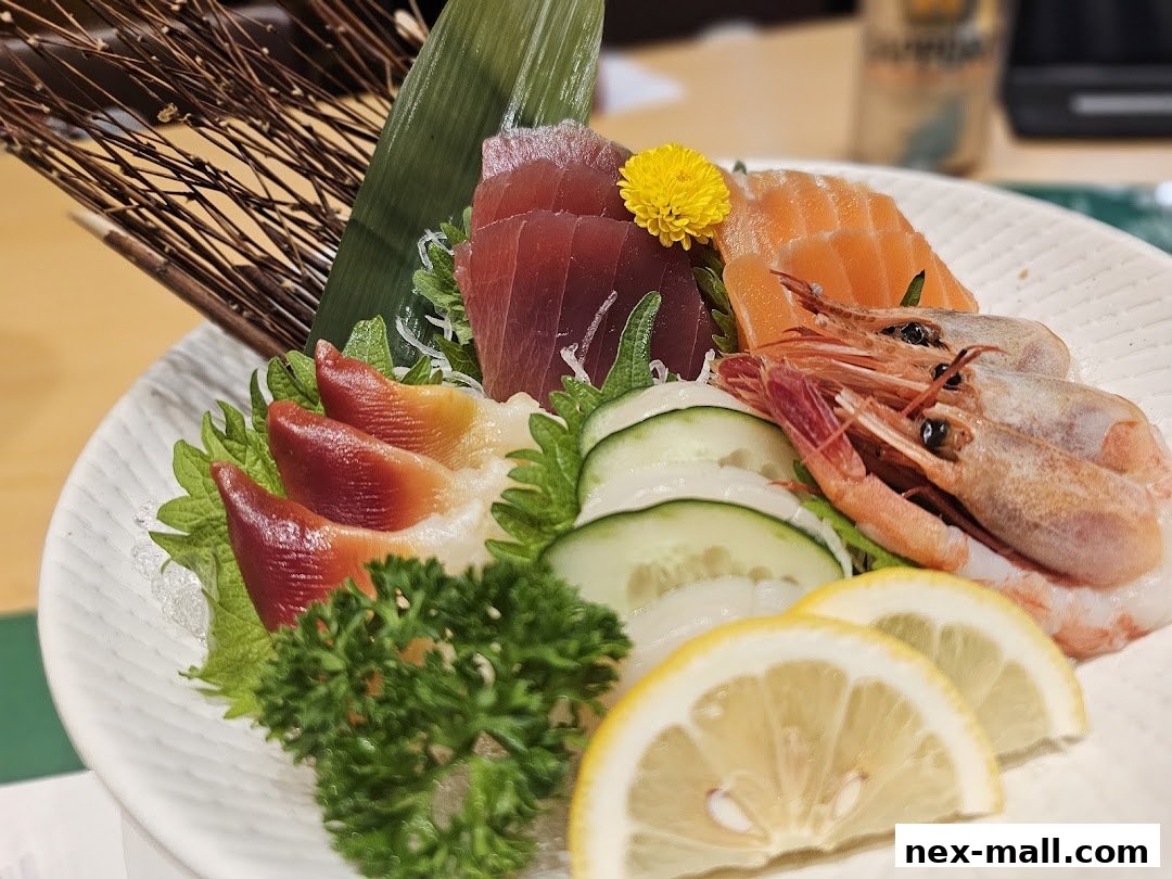 A beautifully presented sashimi platter with tuna, salmon, shrimp, and clams, garnished with lemon and cucumber.