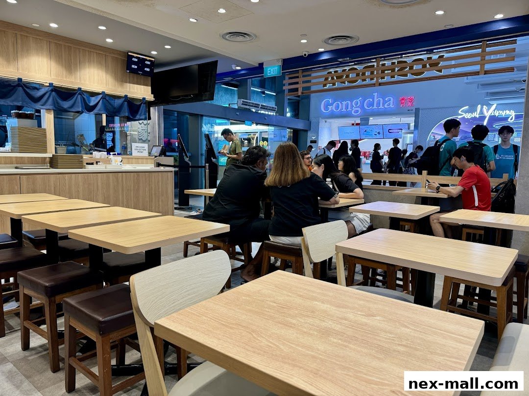 Interior of a food court with multiple dining tables and people seated.