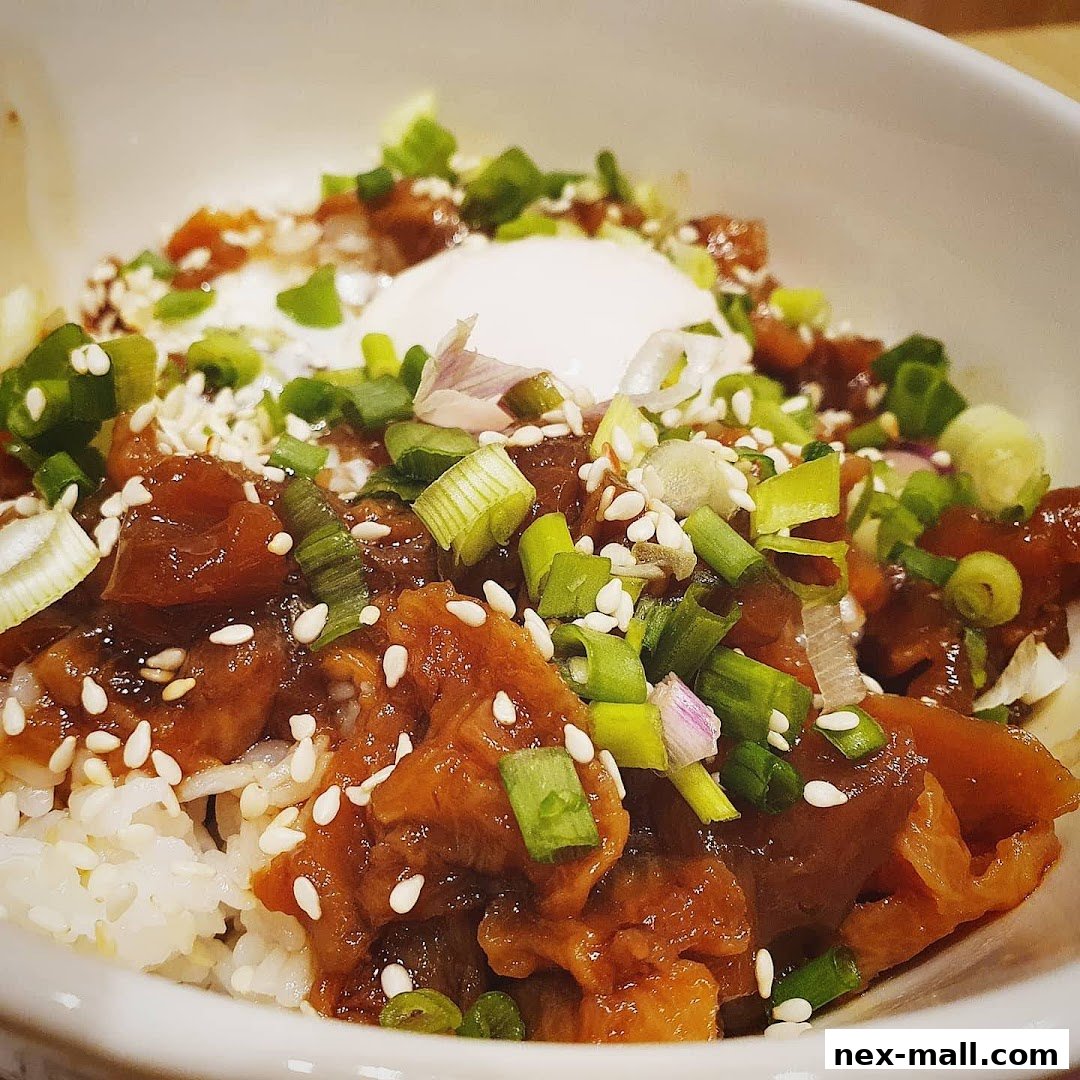 A close-up of a Yoshinoya bowl with rice, meat, and green onions.