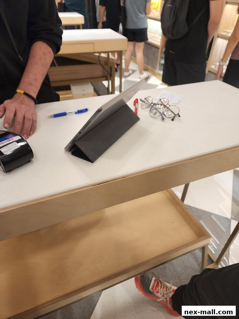 A close-up of a counter with glasses, a tablet, and a payment terminal.
