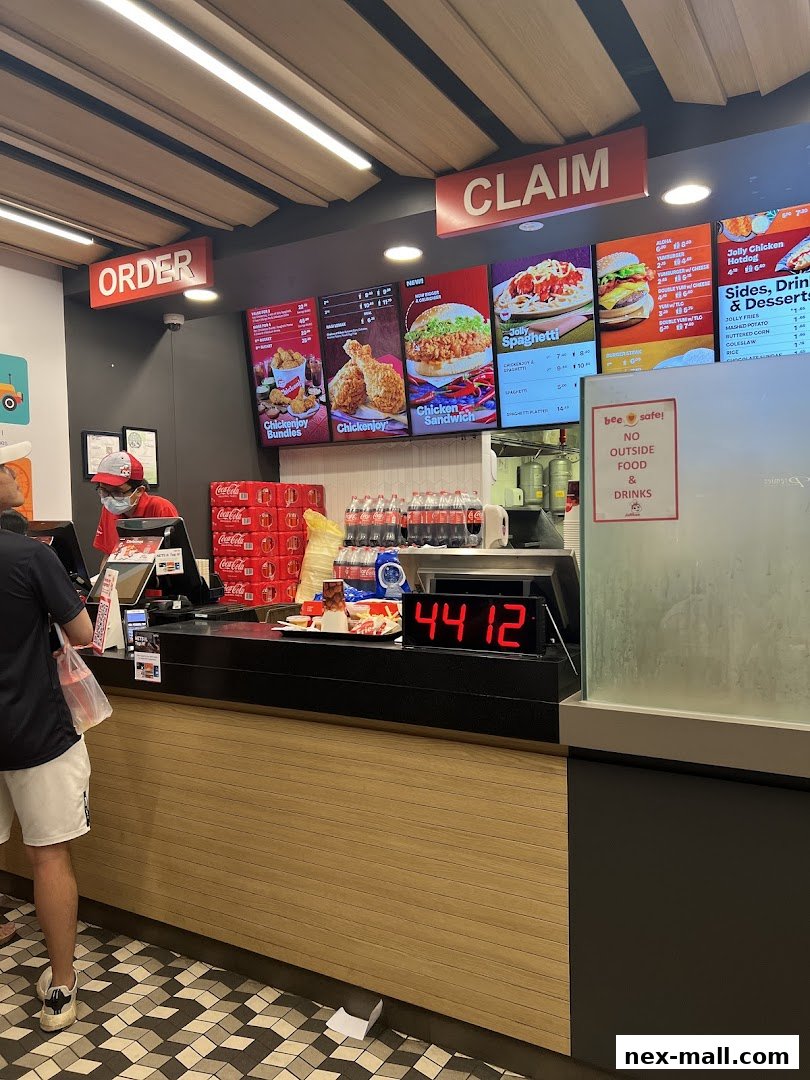 A Jollibee counter with digital menus displaying food items and a customer ordering.