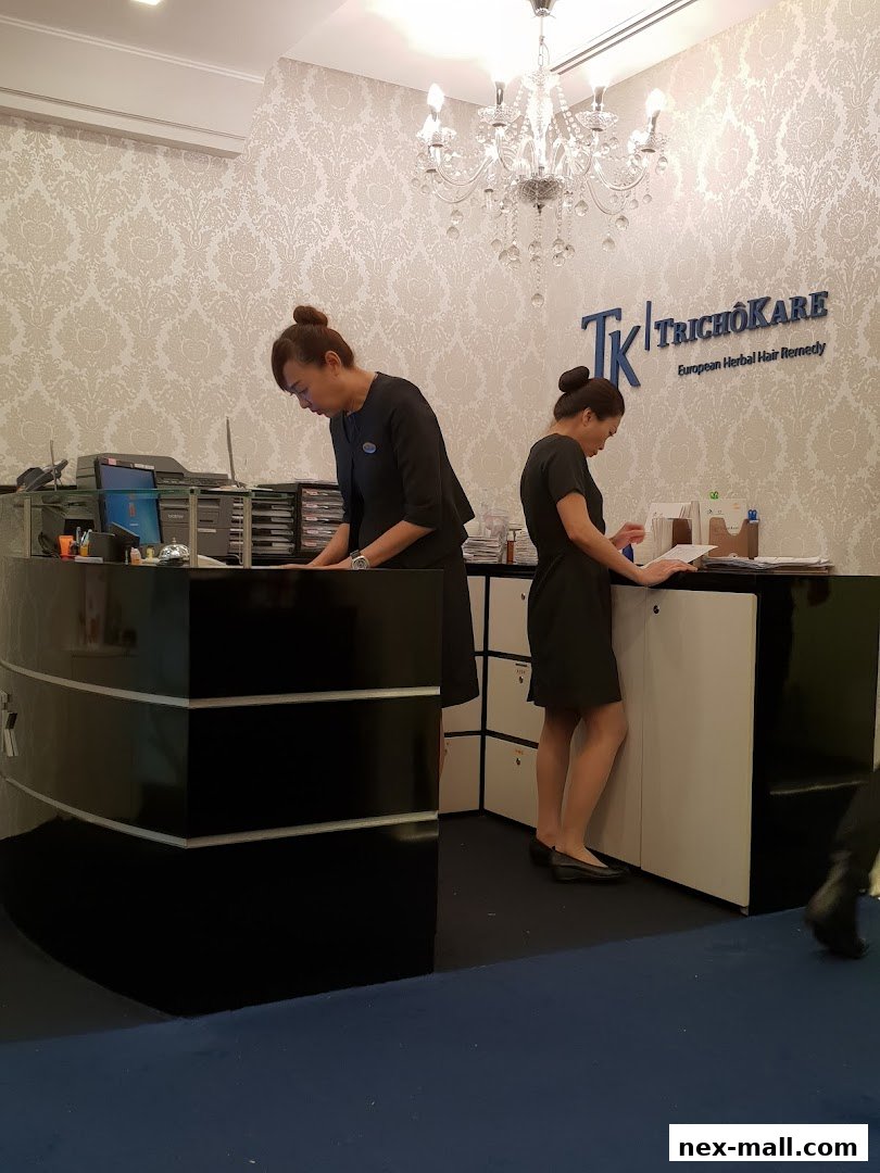 Two women working at the reception desk of a hair loss treatment salon.