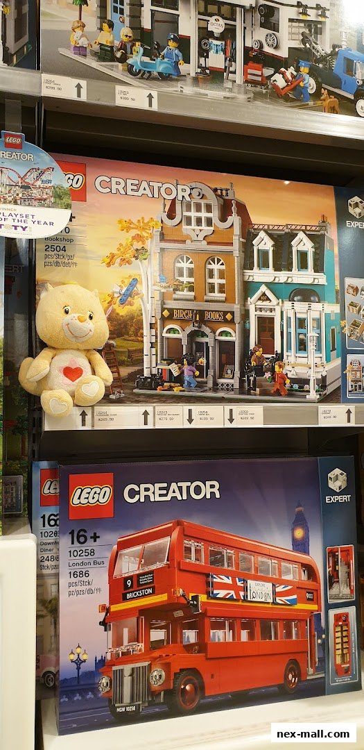 LEGO Creator sets, including a bookshop and a London bus, displayed on shelves with a plush toy.