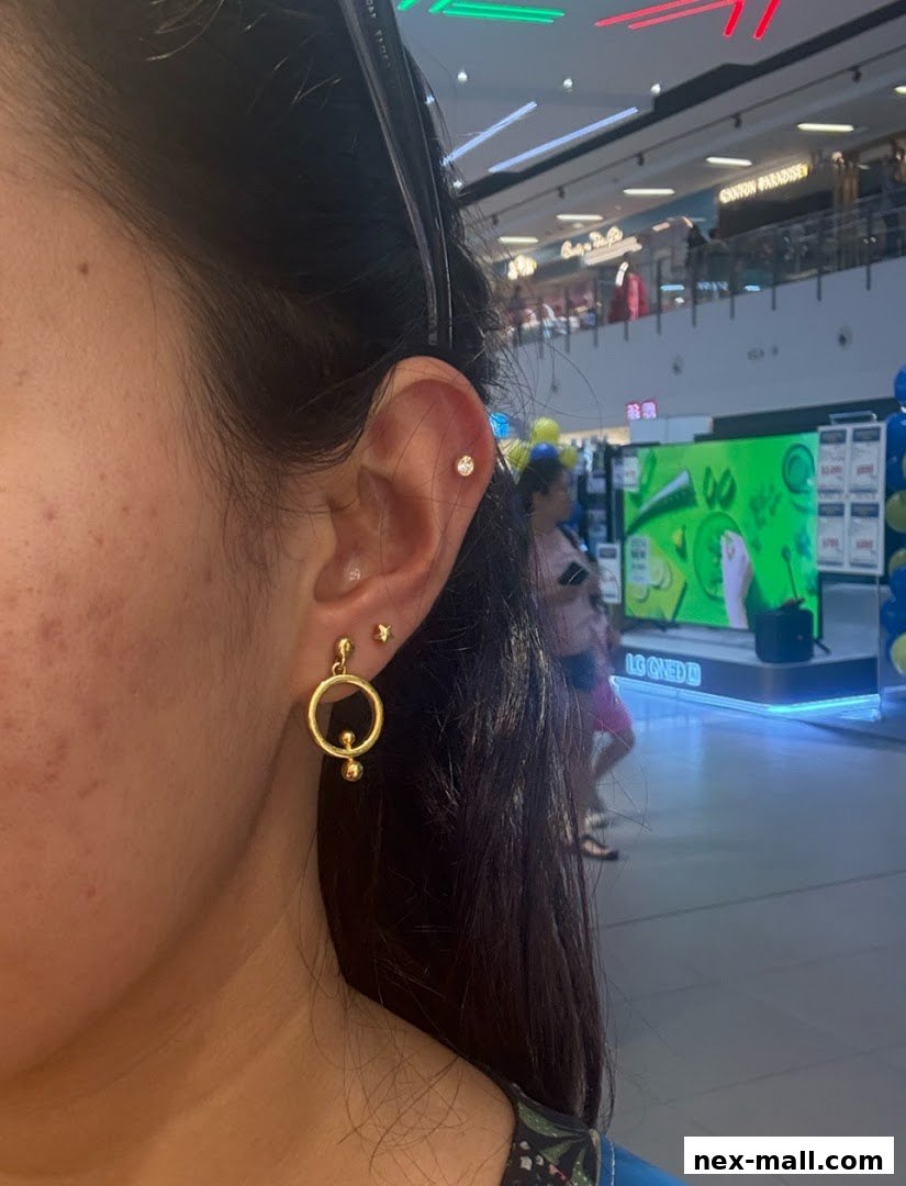 A close-up of a woman's ear adorned with stylish gold earrings and a stud.