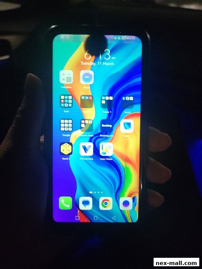 A hand holds a smartphone displaying various app icons and the time.