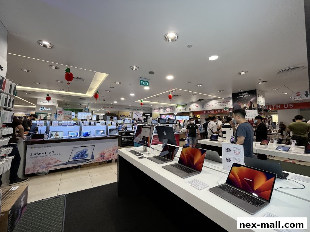 Interior view of a busy electronics store with various laptops and displays.