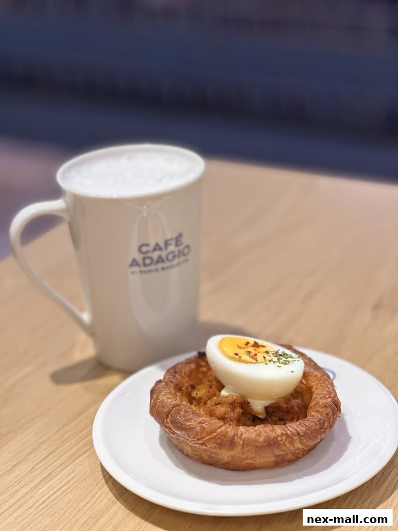 A savory pastry with a boiled egg on top, served with a frothy coffee.