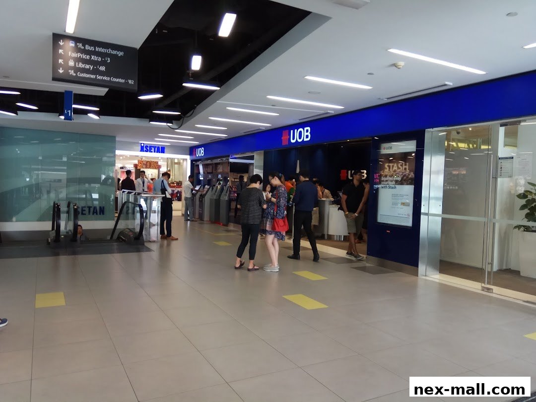 Exterior view of a UOB bank branch with ATMs and customers inside.