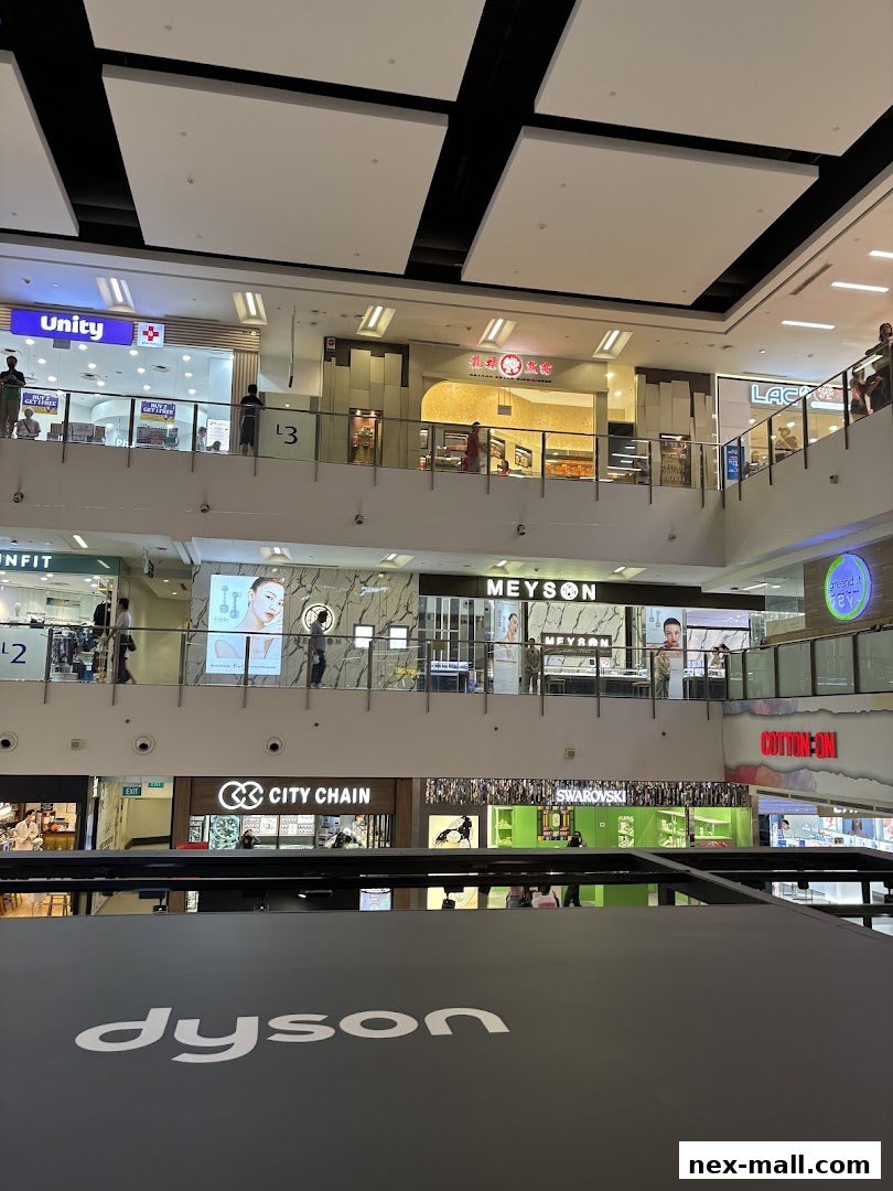 Interior view of a shopping mall with various shops including Dyson, Swarovski, and Cotton On.