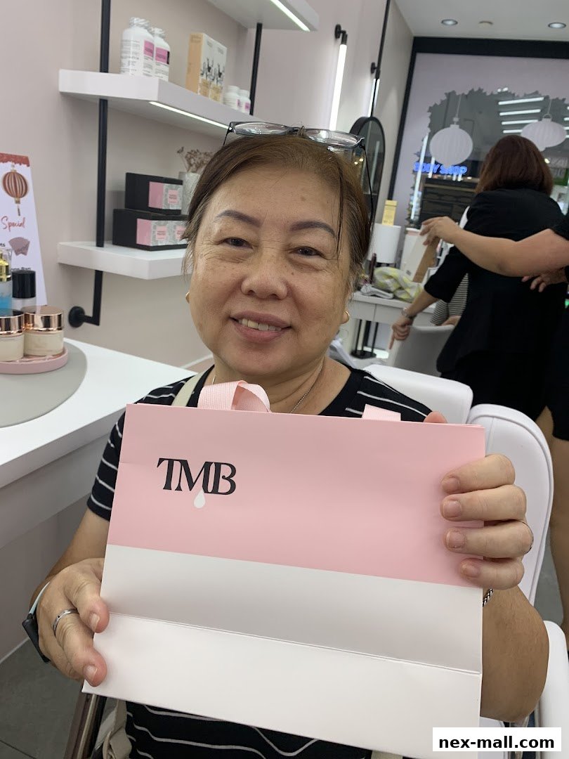 A smiling woman holds a pink and white shopping bag with 'TMB' logo inside a beauty store.