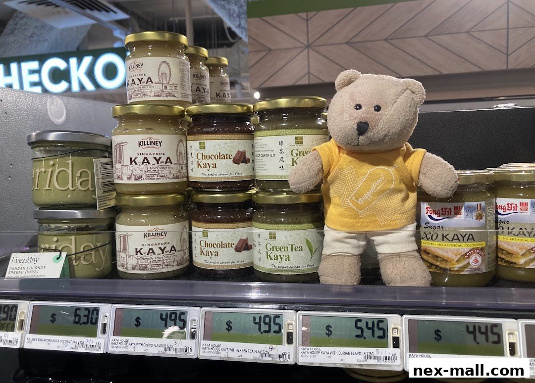 Jars of Kaya spread and a teddy bear are displayed on a shelf in a store.
