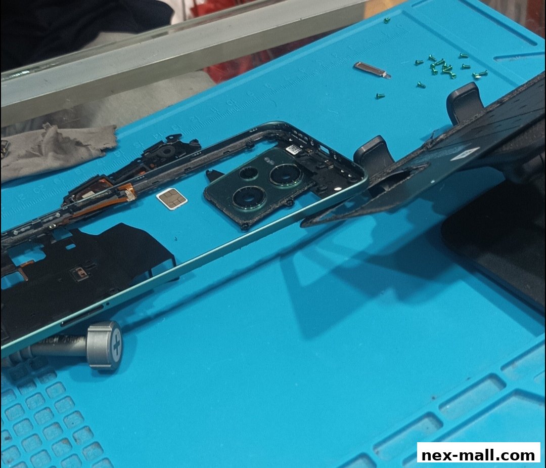 A disassembled smartphone on a blue repair mat with tools and small parts.