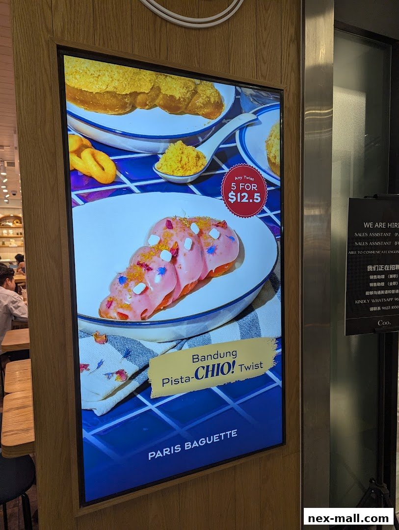 A digital display showcasing a pink pastry with sprinkles and a special offer for Paris Baguette.