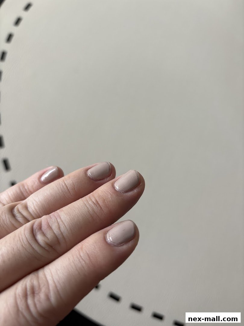 A close-up shot of a hand with neatly painted nude-colored nails.