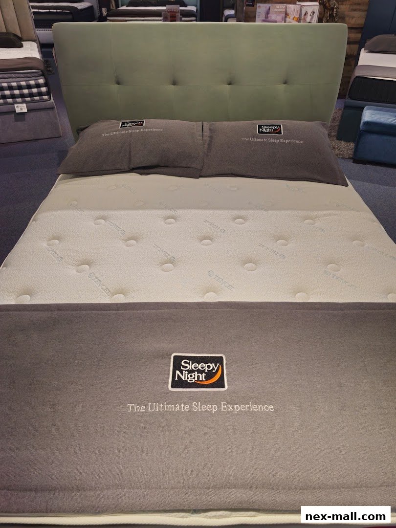 A king-size bed with a light green headboard and two pillows.