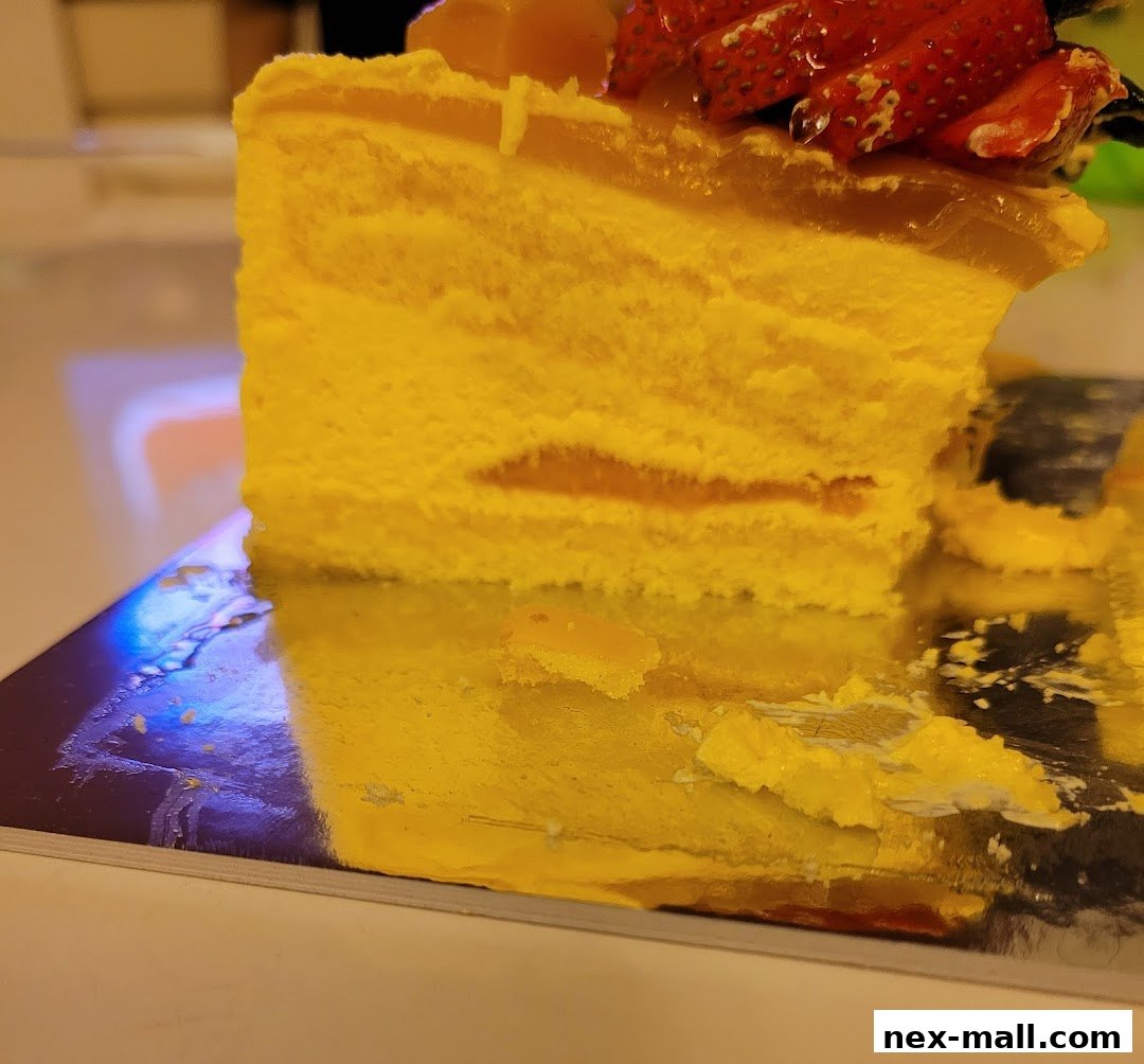 A slice of yellow cake with strawberries and jelly on top, presented on a silver platter.