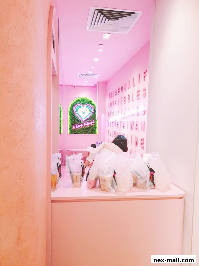 A pink-themed interior of a shop with bubble tea drinks and a neon heart sign.