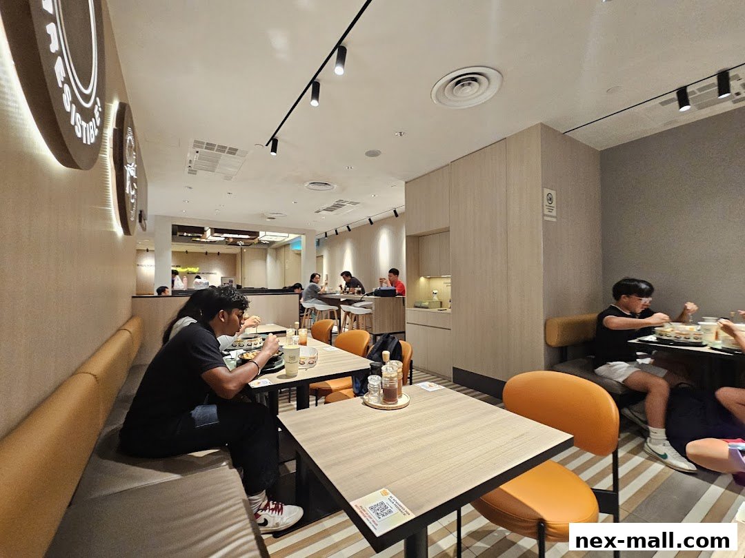 Diners enjoying meals at tables inside a modern, brightly lit Pepper Lunch restaurant.