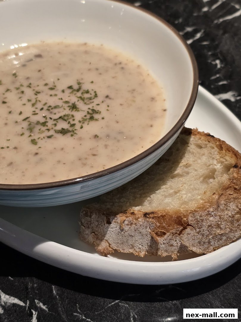 A close-up of creamy mushroom soup with a slice of crusty bread and parsley garnish.
