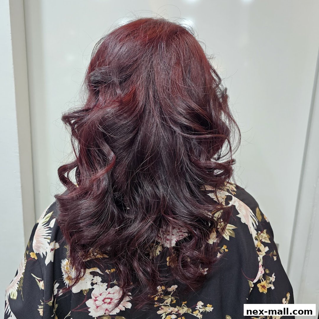 A person's back with styled, dark red, wavy hair.