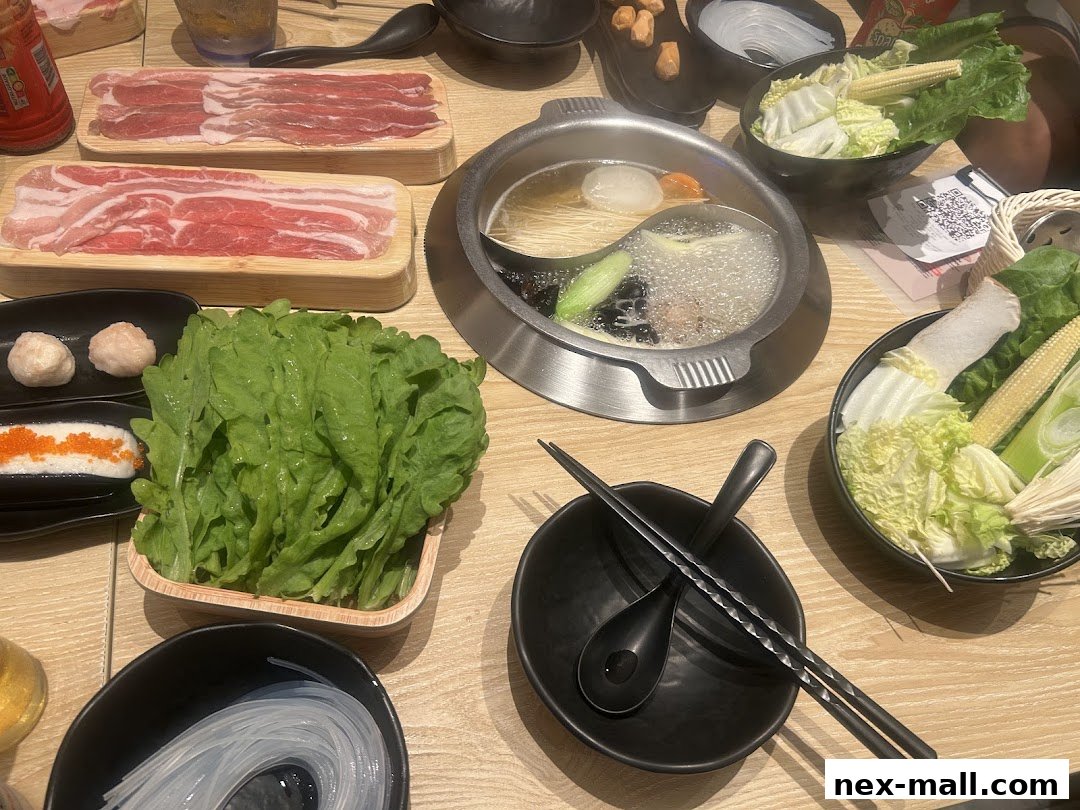 A table laden with fresh ingredients for a hot pot meal, including thinly sliced meats and vegetables.