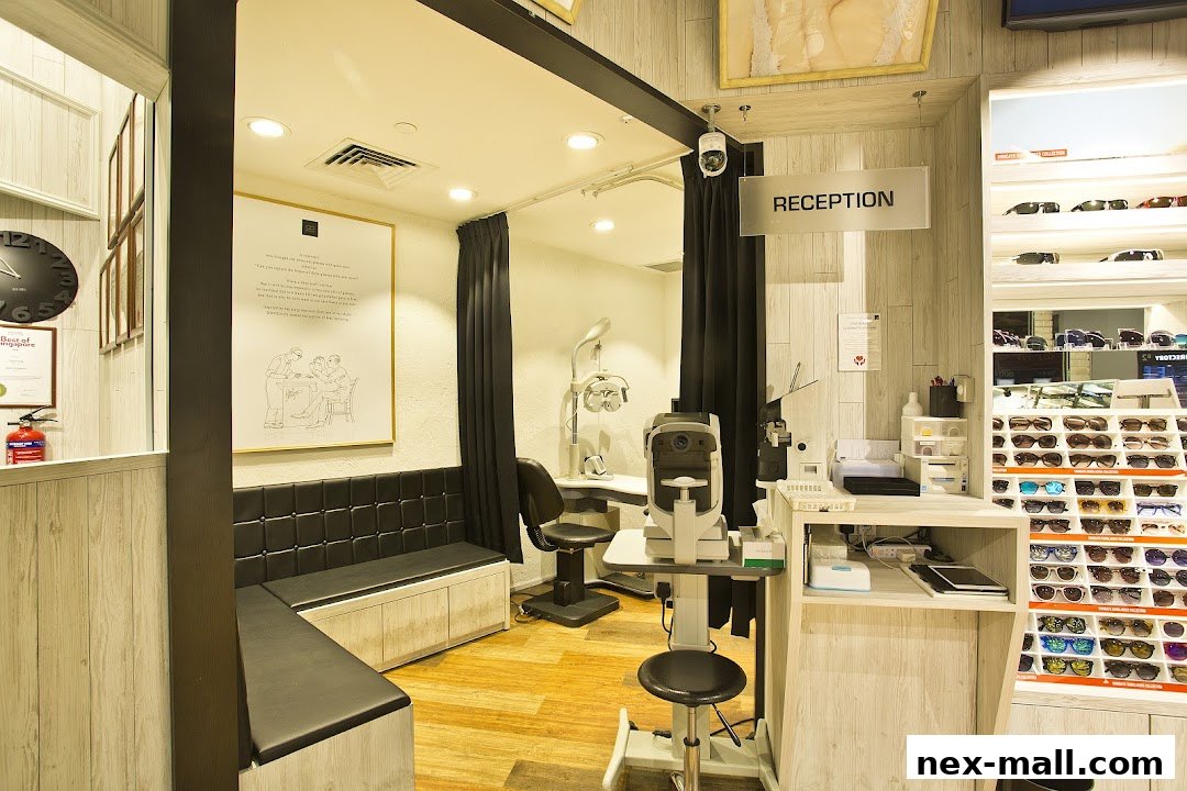 Interior of an optical shop with a reception desk, eye examination equipment, and display shelves of eyeglasses.