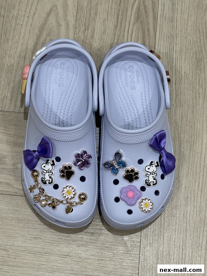 A pair of light purple Crocs adorned with various Jibbitz charms, including Snoopy and flowers.