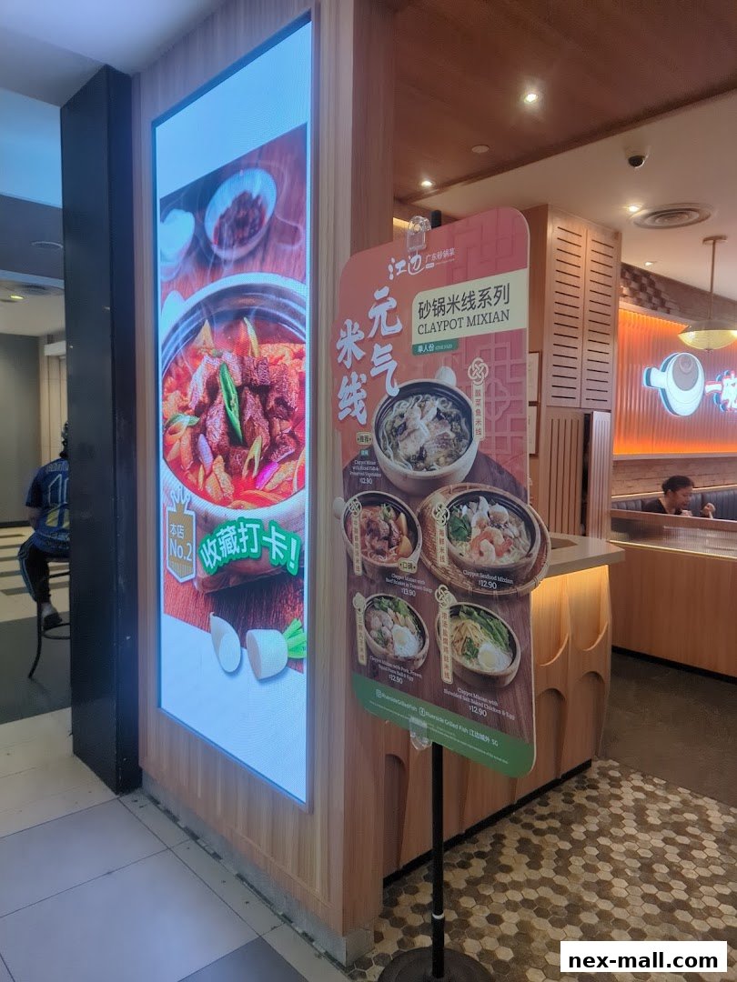A sign displays claypot dishes outside a restaurant with a digital screen showing food.