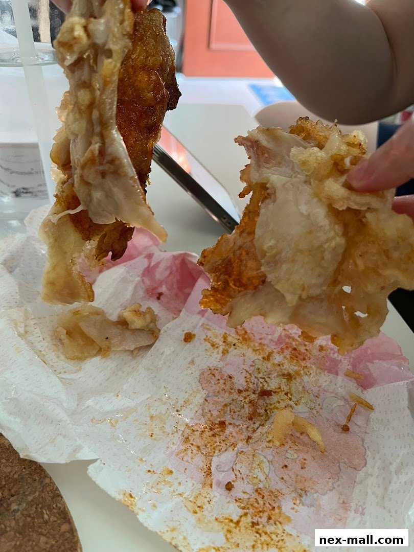 Close-up of crispy fried chicken pieces being held over a paper towel.