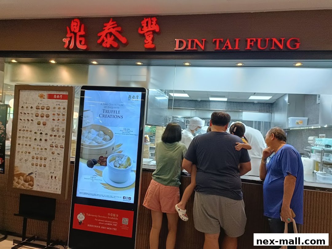 People queue at Din Tai Fung, with a digital menu displaying truffle creations and a traditional menu board.