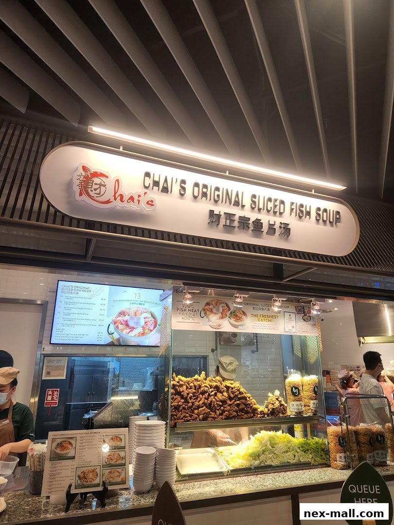 A food stall counter with a menu, fresh ingredients, and fried fish.