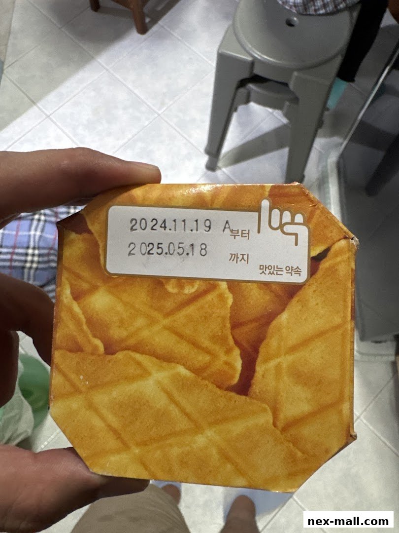 A hand holds a box of waffles with a label showing production and expiration dates.