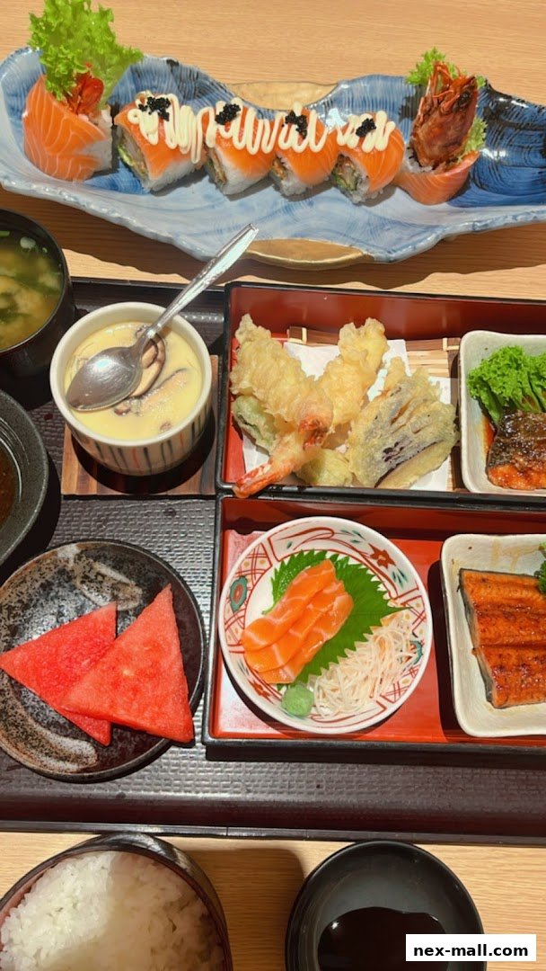 A delicious Japanese meal featuring sushi rolls, tempura, sashimi, grilled fish, and watermelon.