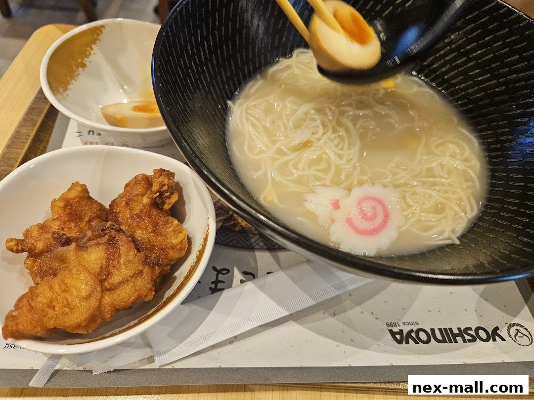 A close-up of a Yoshinoya meal featuring ramen, fried chicken, and a soft-boiled egg.