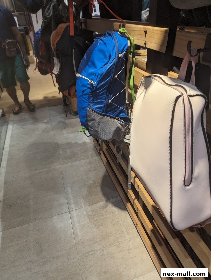 A selection of backpacks and bags are displayed on wooden shelves in a retail store.