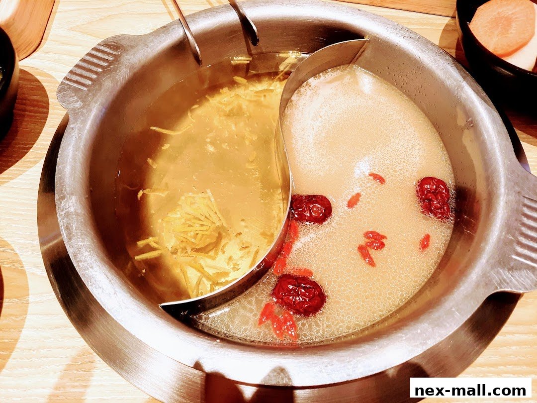 A split hot pot with two different broths, one clear with ginger and one creamy with goji berries and red dates.